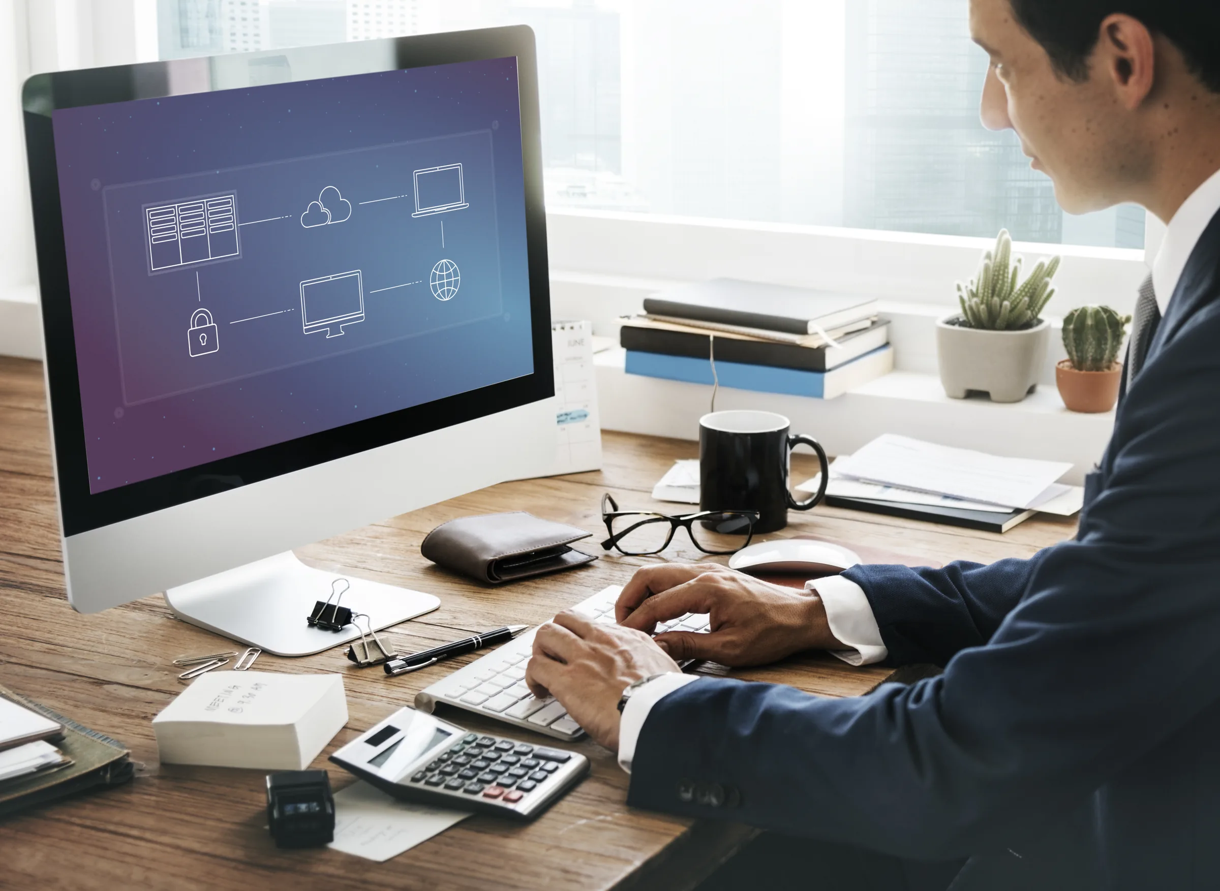 Man in a suit at a desktop computer showing a cloud systems diagram
