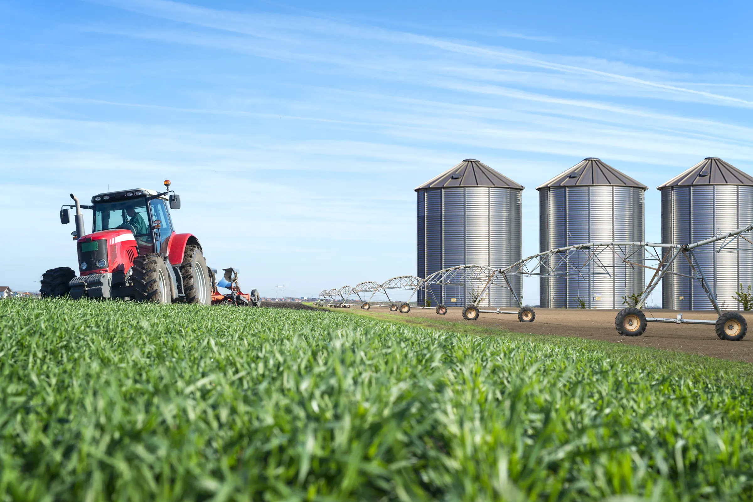 Tractor and grain silos under an open sky, representing agri-food operations built for seasonal swings