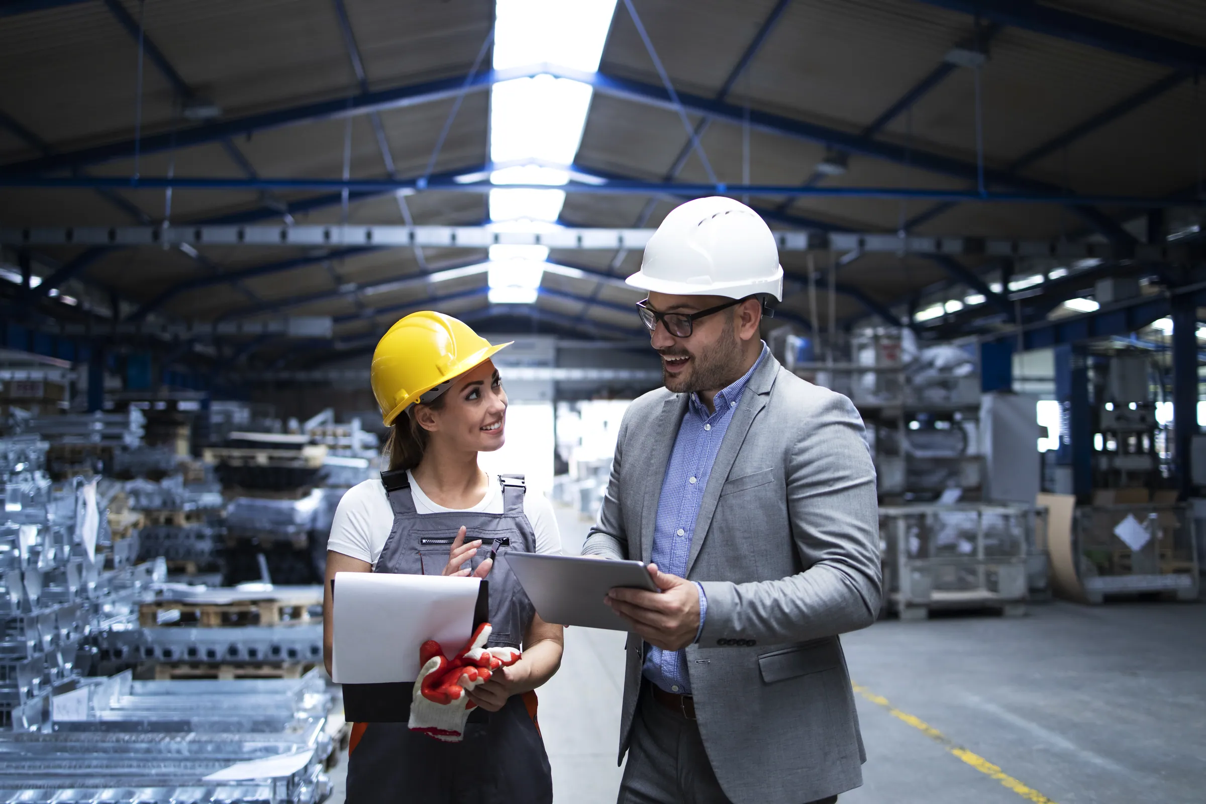Project manager in a suit and hard hat with a technician on site, representing engineering and construction delivery