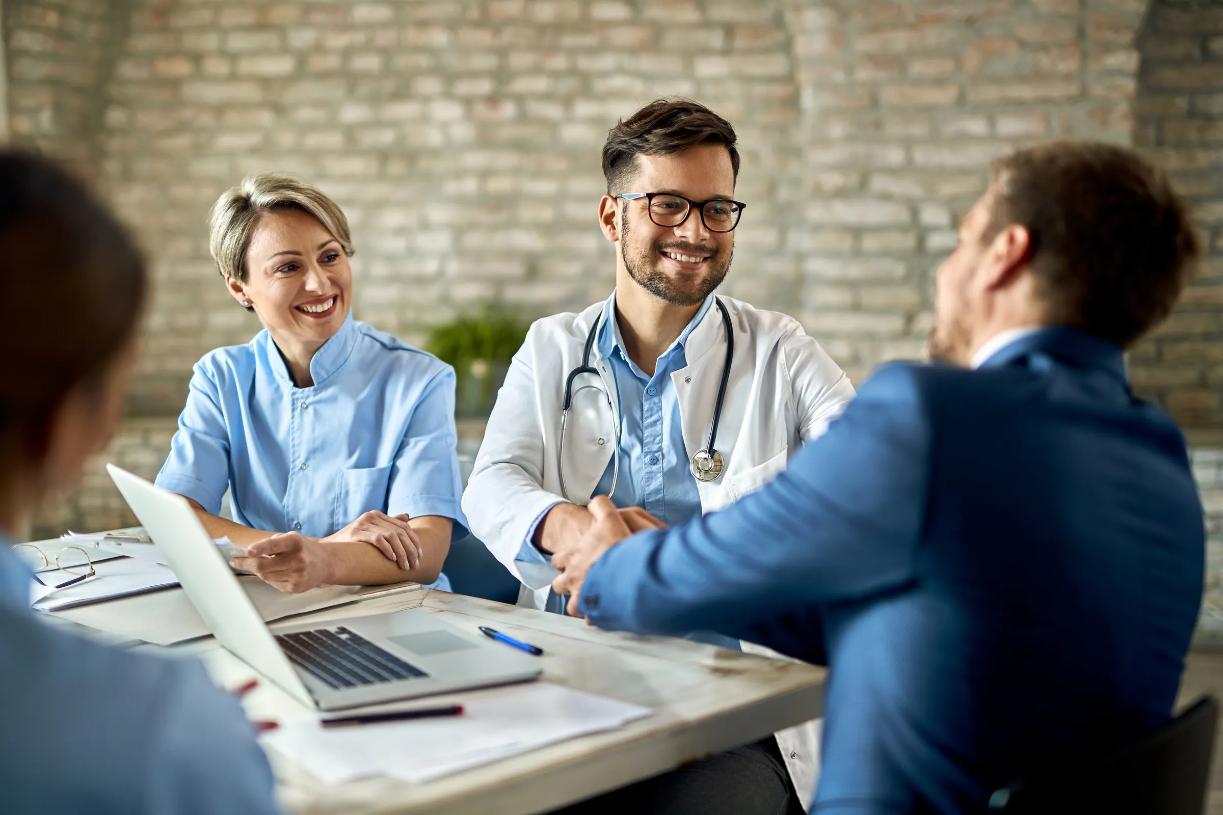 Clinicians meeting a colleague in business dress in a hospital, representing healthcare and life sciences data