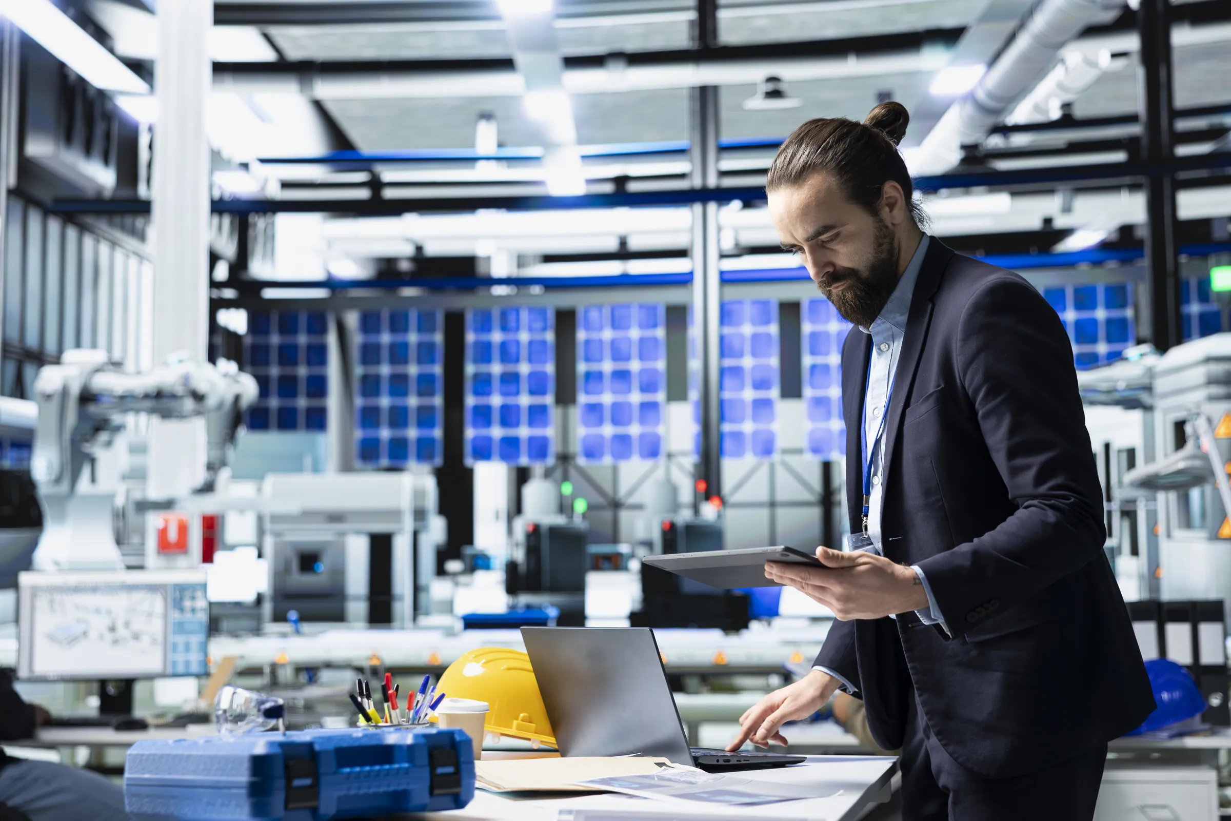 Engineer in a dark suit reviewing a tablet beside solar panels