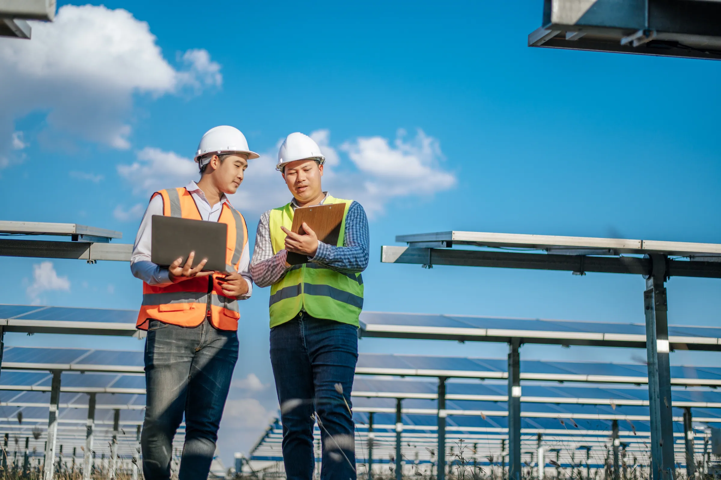 Two technicians on a solar farm under open sky