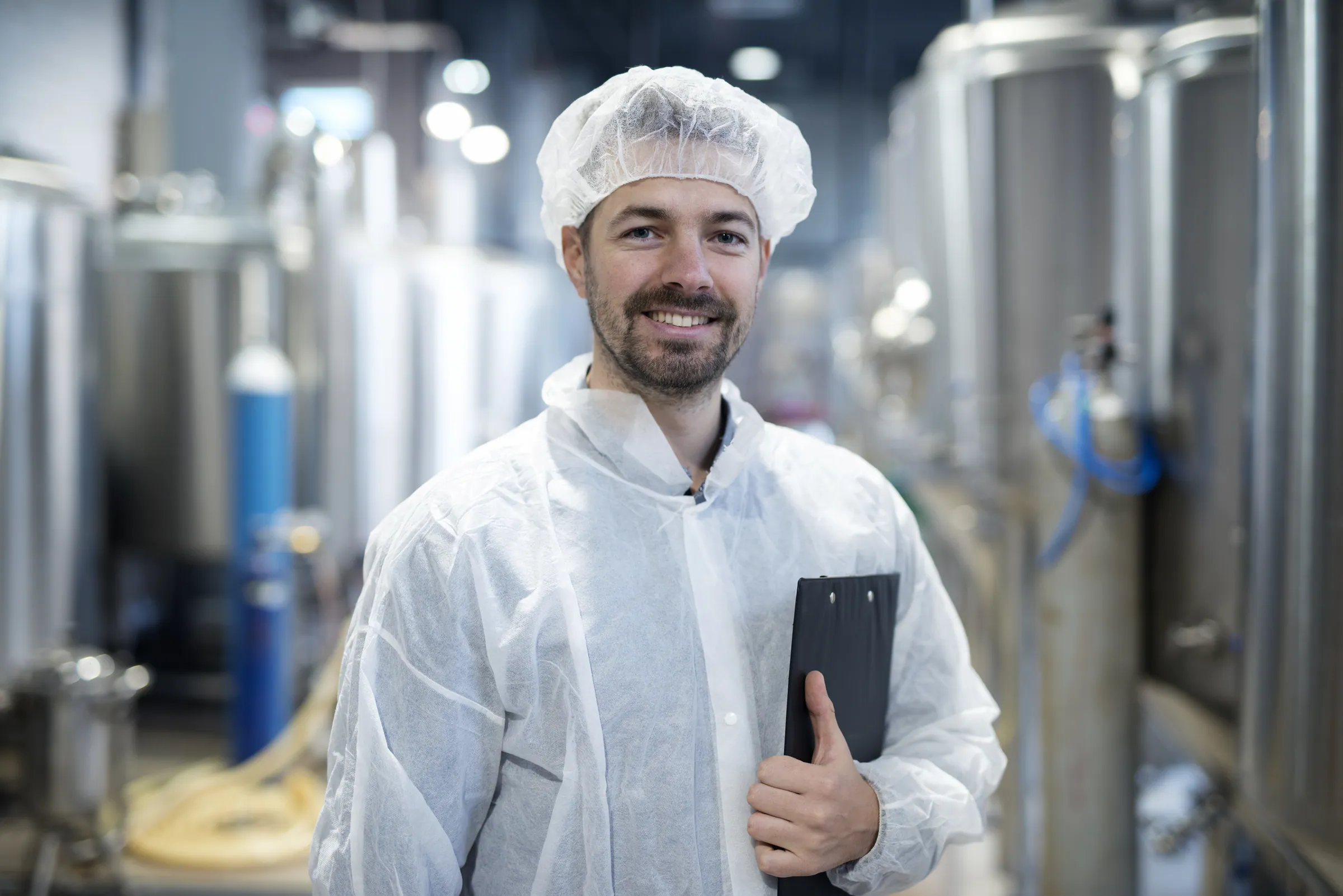 Technologist with a clipboard beside processing tanks