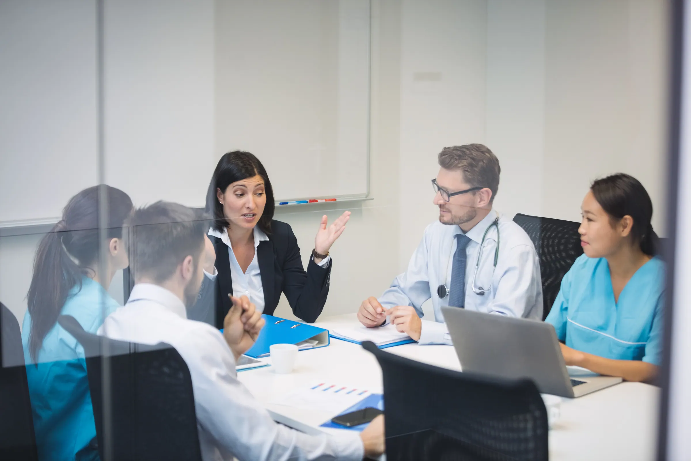 Manager in a suit briefing a clinical team