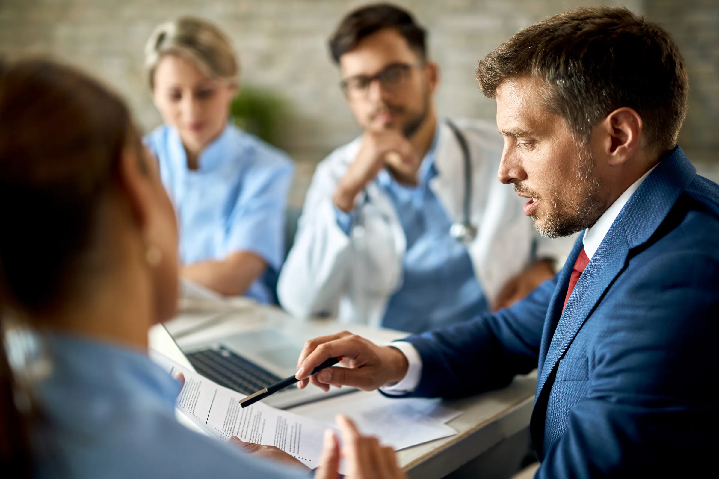 Sales lead in a suit reviewing documents with clinicians