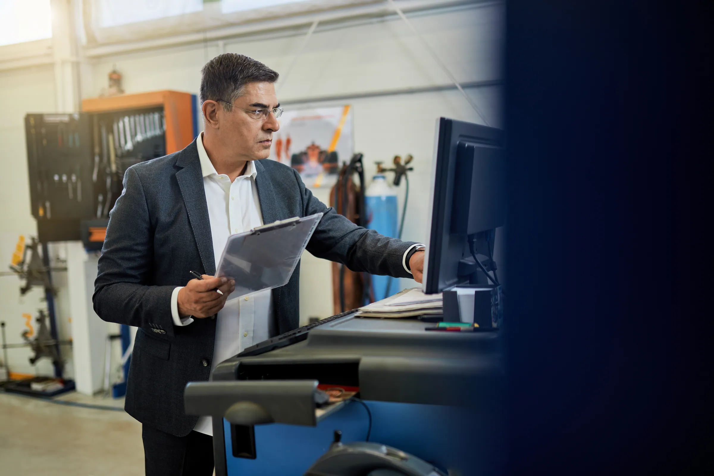 Inspector in a suit checking data at a shop floor terminal