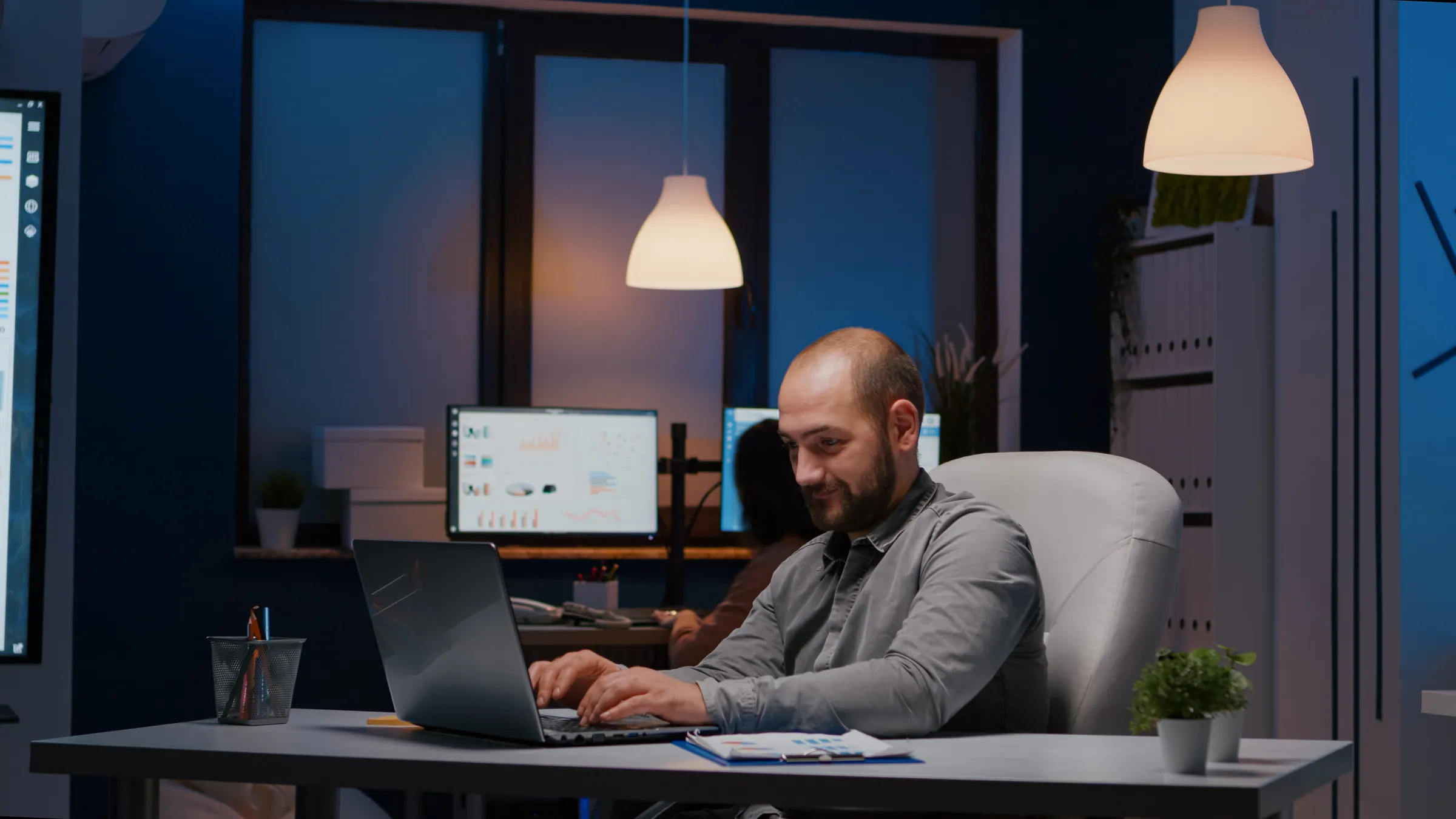Analyst at dual monitors in a blue-lit office