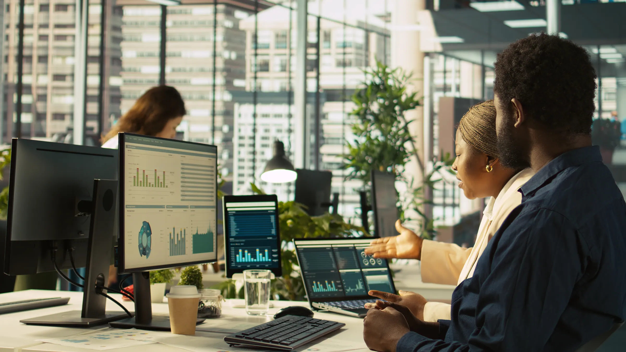 Two colleagues in business dress at analytics monitors