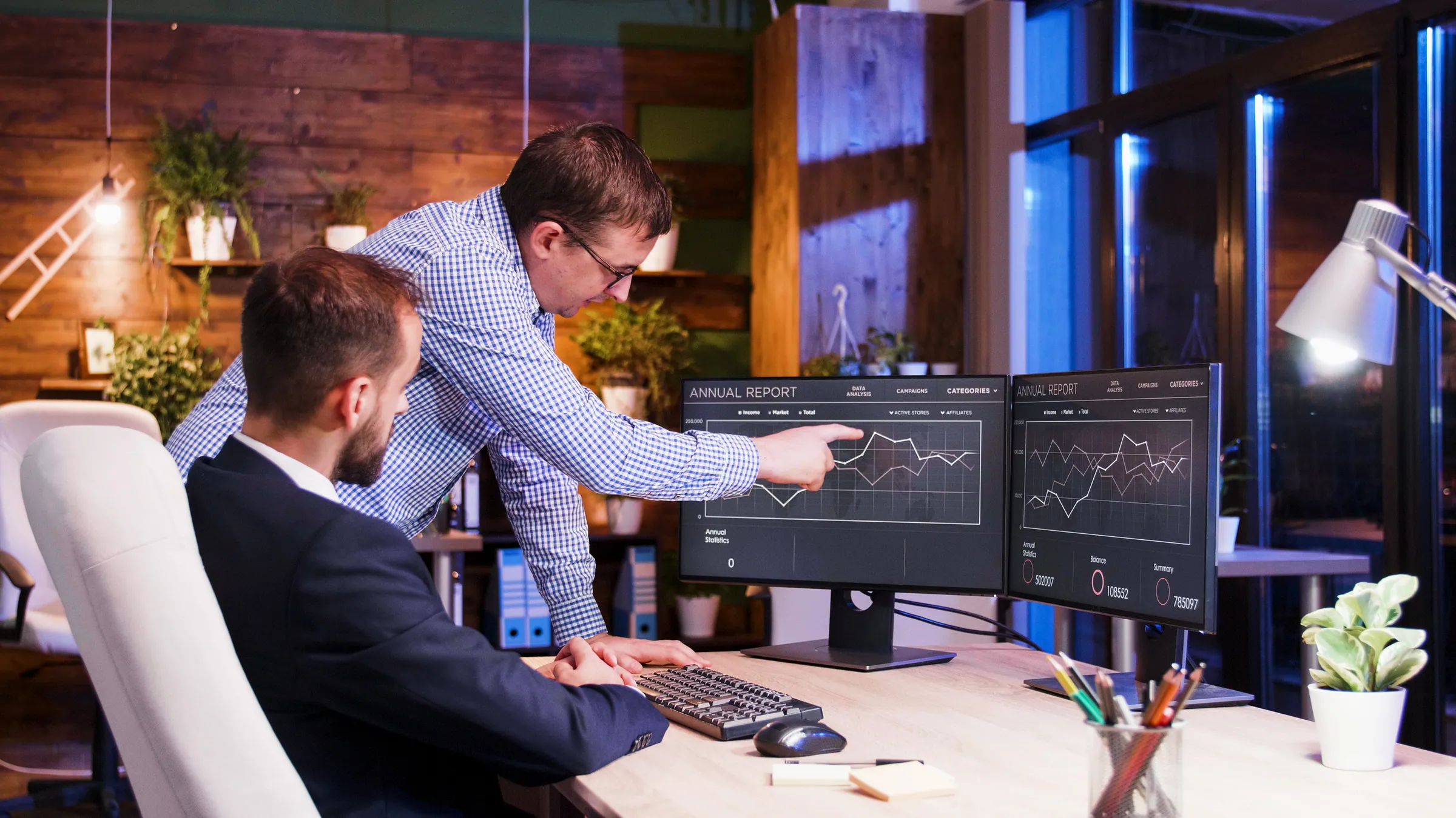 Analysts reviewing data dashboards in a blue-lit office, representing a trusted enterprise data foundation