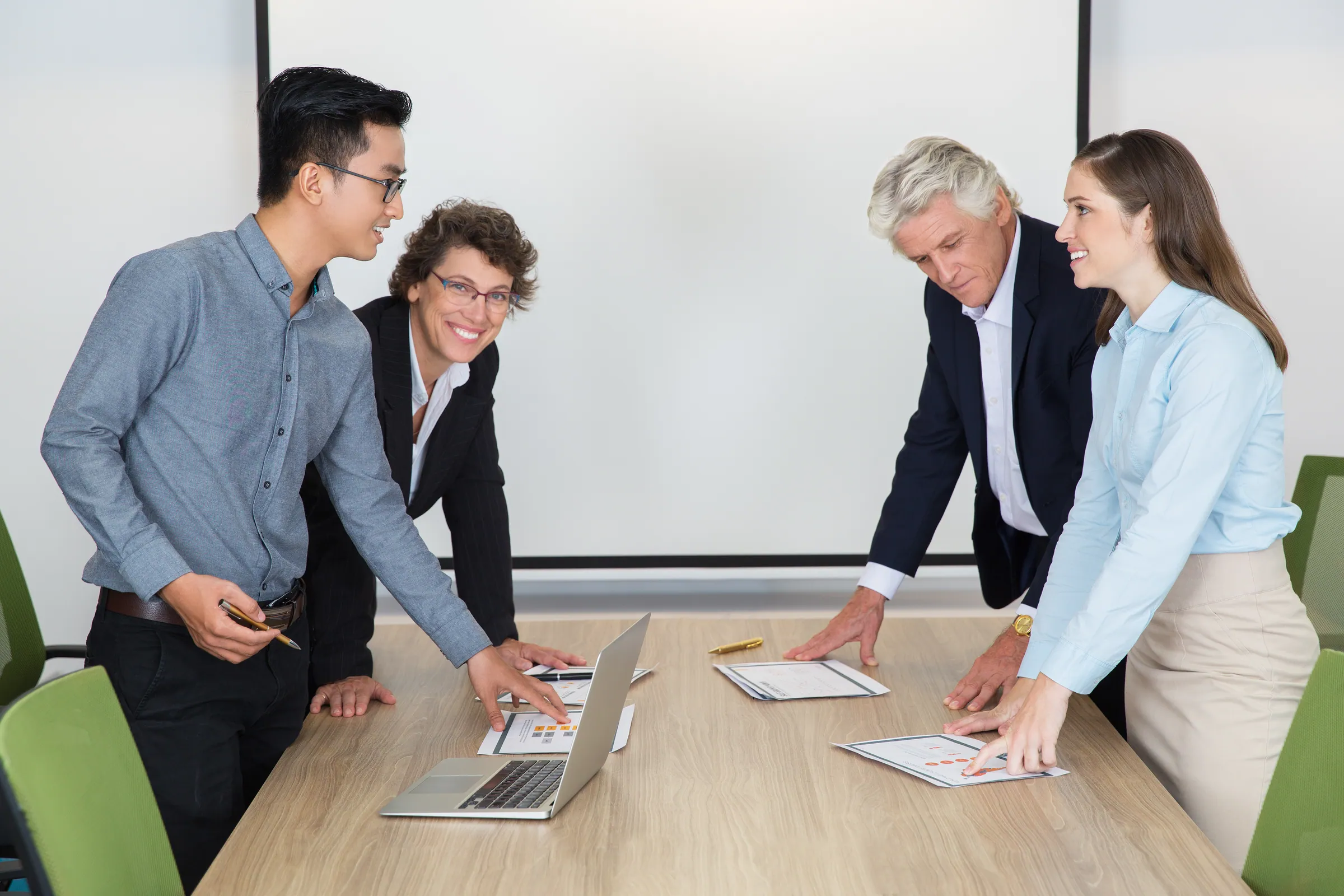 Colleagues in business dress reviewing plans across a meeting table, representing a governed Microsoft Dynamics 365 estate