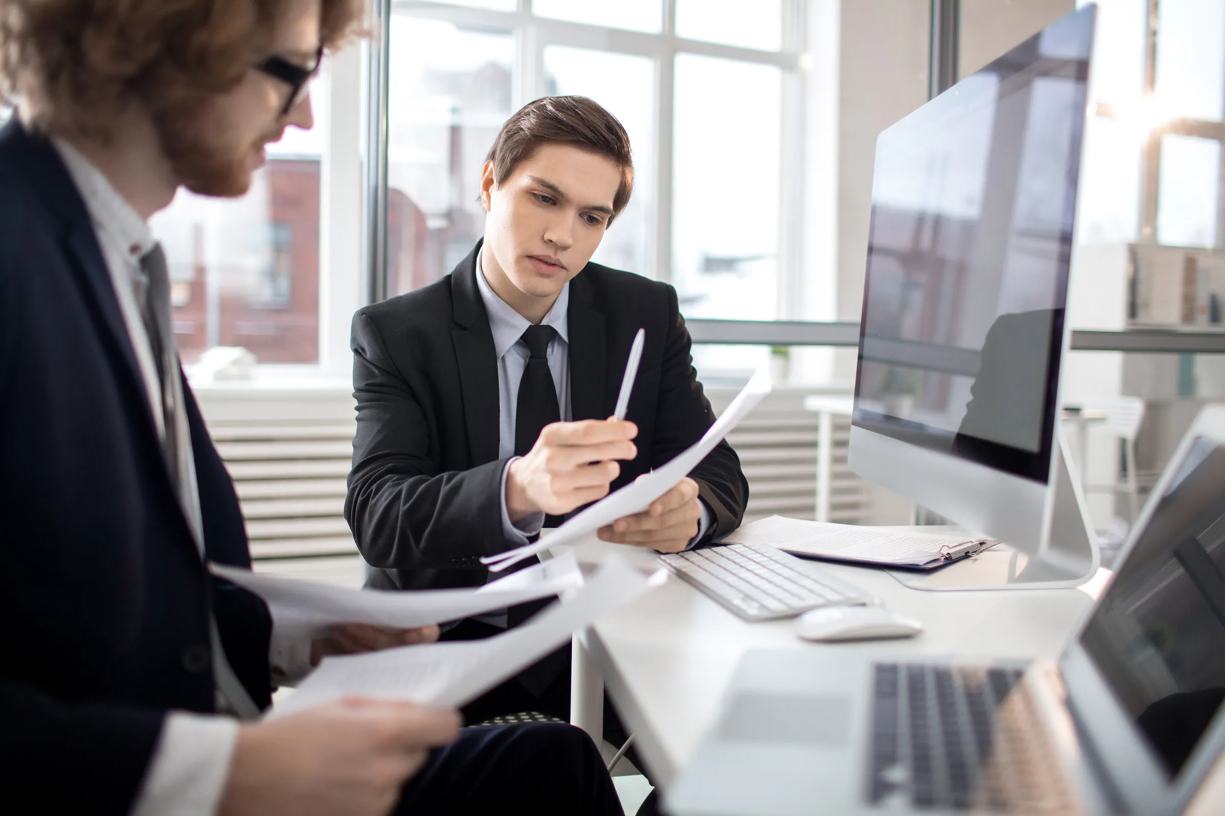 Two delivery colleagues in suits working through project documents, representing enterprise project delivery