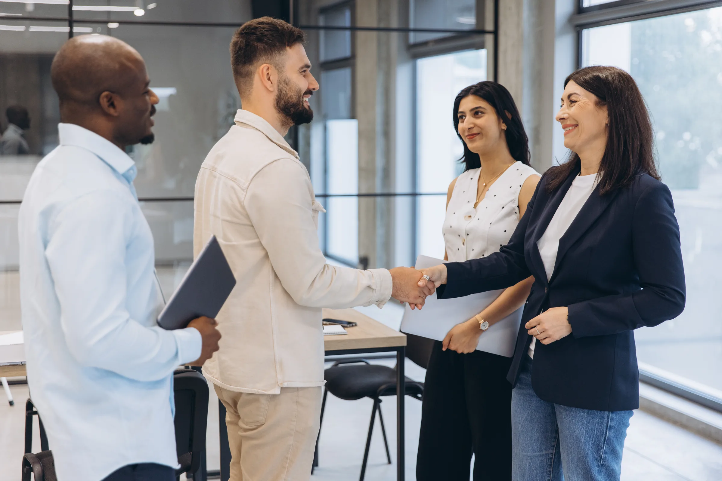Colleagues shaking hands in a bright open plan office